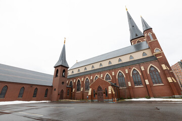 Obraz premium The Cathedral of the Immaculate Conception in Portland, Maine, stands tall in warm sunset light. Its striking red brick facade and Gothic Revival architecture make it a landmark in the city