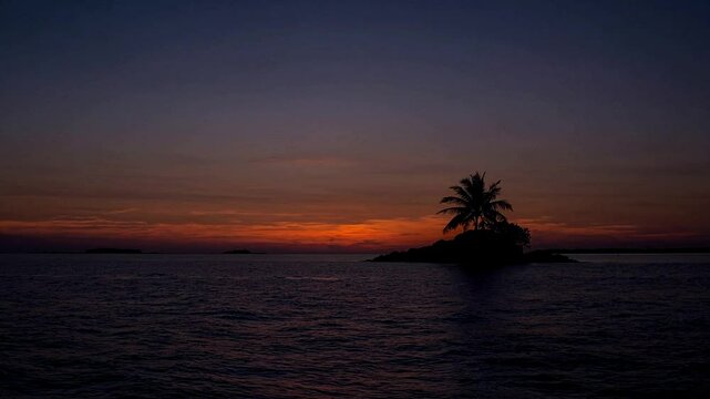 Wide Shot Sunset over the horizon with silhouettes of a coconut tree on the middle of tiny island, fiery orange and deep blue tones, warm, fading light, mood of awe and timeless beauty.
