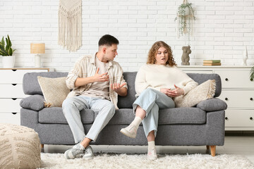 Fototapeta premium Angry young couple quarreling on sofa at home