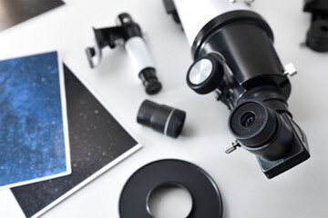 Detail of a telescope eyepiece on white table with photographs