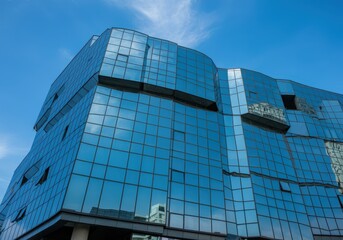 Fototapeta premium A modern glass building reflecting the sky, creating an abstract architectural view.