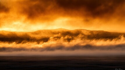 A beautiful sunrise illuminates rolling hills with dense atmospheric clouds