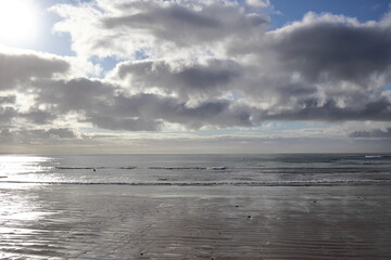 Scenic beach along the Great Ocean Road, Victoria, Australia, with dramatic clouds and calm waves. Tranquil coastal view with a vast sandy shore and gentle ocean surf under a cloudy sky.