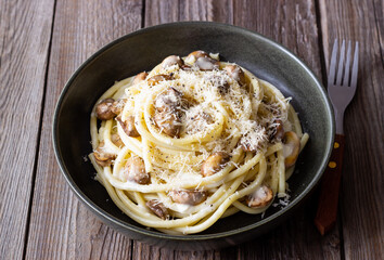 Bucatini pasta in creamy sauce with mushrooms and cheese. Vegetarian food. Italian cuisine.