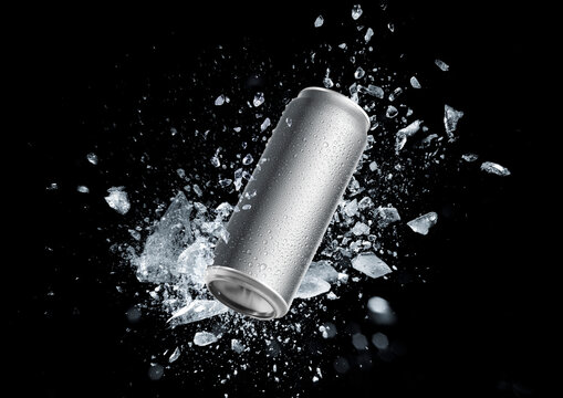Aluminum beverage can bursts out of the ice cube isolated on black blackground.