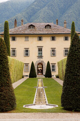 Italian famous historical antique villa Balbiano surrounded with pine trees at Como Lake,...