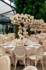 modern classic floral wedding decoration with lots of roses on the tables with wooden chairs in Italian villa, destination wedding 