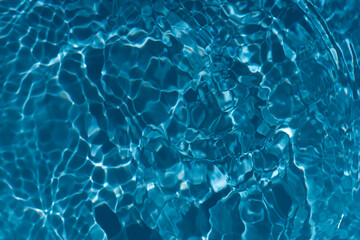 Blue water with ripples on the surface. Defocus blurred transparent blue colored clear calm water surface texture with splashes and bubbles. Water waves with shining pattern texture background.