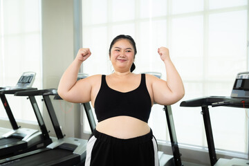 Fototapeta premium Happy Asian overweight woman lifting up dumbbell two arms in fitness club, healthy strong chubby females wearing sportswear exercise building muscles, happy curvy girls in weight loss workout training