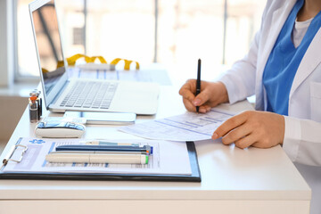Fototapeta premium Female doctor working with form at desk in office, closeup