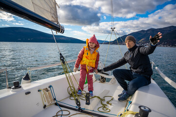 Father instructing daughter on sailing a yacht during training in the Kotor Bay, Montenegro,...