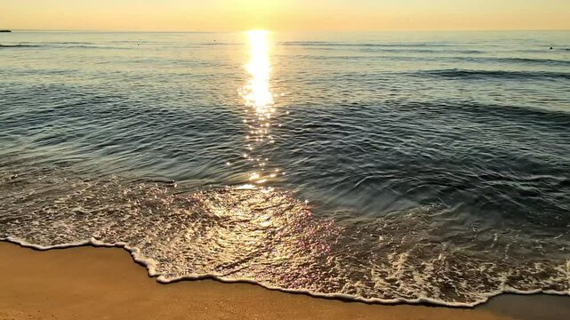 Le soleil levant, en montant vers le ciel, cr&eacute;e un sillage dor&eacute; &eacute;blouissant et vibrant &agrave; la surface de la mer.