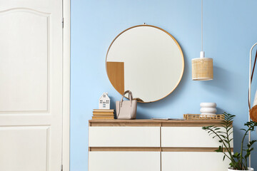 Chest of drawers and mirror on blue wall in hallway