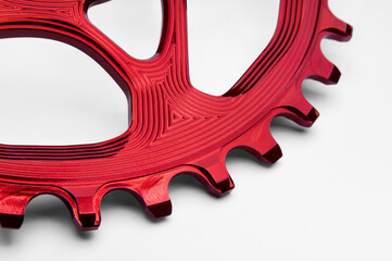 Close up of a red oval bicycle chainring against white isolated background, lies flat on the...