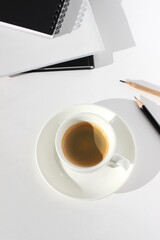 Cup of Coffee, Notebooks, Pencils on White Background. Coffee Break at Workplace. Business Meeting Concept.	