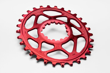  Red oval bicycle chainring against white isolated background, lies flat on the surface....