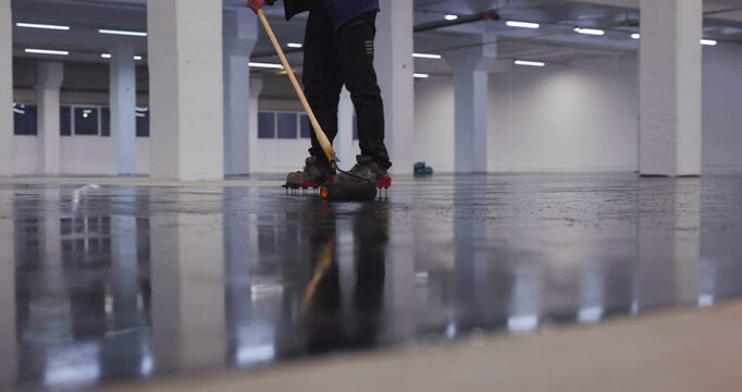 Construction worker applying epoxy resin on a large industrial floor