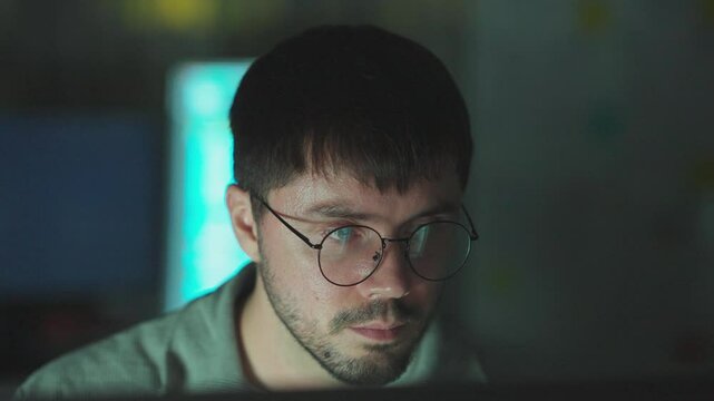 Male network analyst in office, using computers to solve programming challenges and tech problems.
