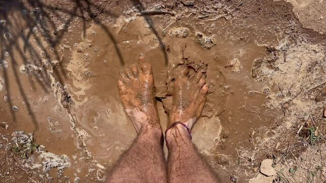 Man's feet jumping in a mud puddle. Grounding or earthing concept. Contacting the energy of nature through the feet