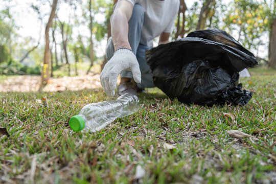 Close-up of a volunteer picking up plastic waste during a community cleanup event.