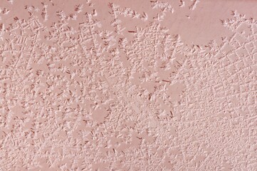 Intricate ice crystals create a delicate frosty pattern on a rosy pink surface, a winter wonder.