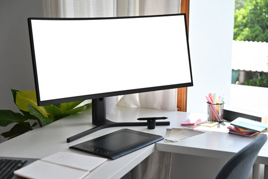 A workspace featuring a curved monitor with empty screen, digital drawing tablet, and color palettes, creating an ideal environment for graphic design, digital art, and creative projects