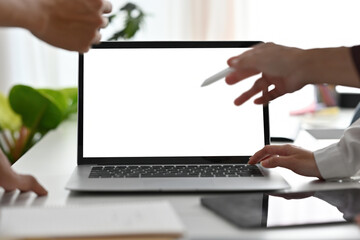 Hands gesture around a laptop screen emphasizing teamwork and discussion. The blank screen represents new ideas, brainstorming, and digital collaboration in a professional setting