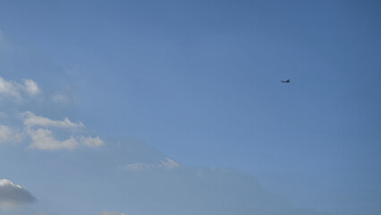 Airplane flying in blue sky with few clouds in prague