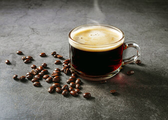 Hot coffee glass cup  and coffee beans on gray background, espresso coffee in a transparent cup with crema