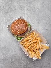 Hamburger and french fries served in cardboard container on gray background galentines day