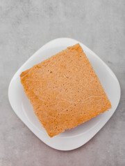 Square slice of sponge cake on white plate on marble table mothers day