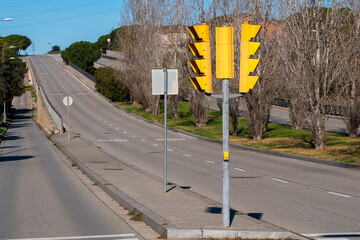 Traffic light at an empty suburban road with natural surroundings.