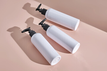 Three white bottles of bath products on a powdery pink background.