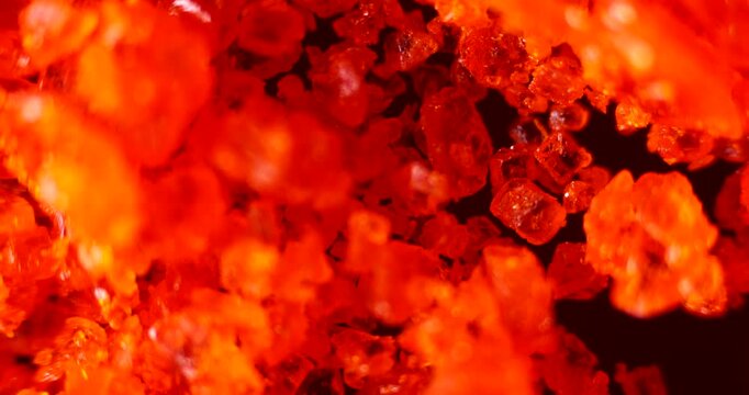 High-magnification footage of orange-red dichromate crystals showing pyrotechnic and chemical reaction properties