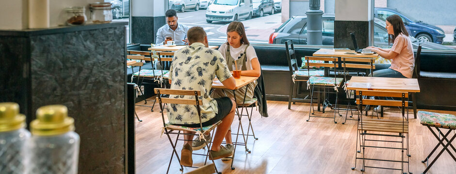 Banner of customers enjoying coffee and working on laptops in a bright, inviting cafe, capturing the essence of modern cafe culture and urban lifestyle in a lively and social atmosphere