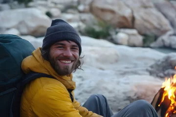 Fototapeten Smiling backpacker relaxes by a campfire amidst rocky terrain, embodying adventure and the joy of outdoor exploration © Татьяна Евдокимова