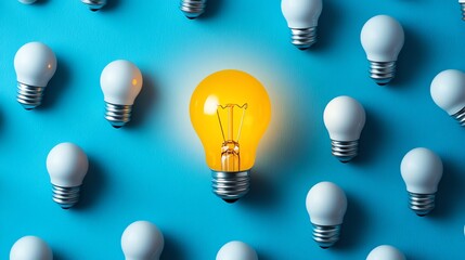 A glowing yellow light bulb surrounded by white bulbs on a blue backdrop, illustrating creativity, innovation, and the illumination of new ideas