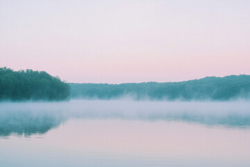 Fototapeta premium Serene lake at dawn with a gentle mist rising from the calm waters and lush green forests in the distance, under a pastel pink sky.