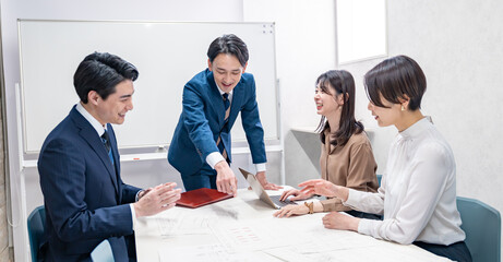 資料を見て会議をするビジネスマン四人