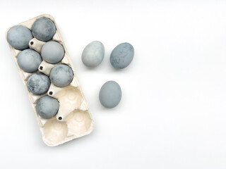 minimalistic easter composition with natural dyed colorful eggs in paper tray on white background. template with space for text. white