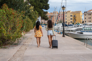 Tourists walking near the marina with luggage during summer vacation
