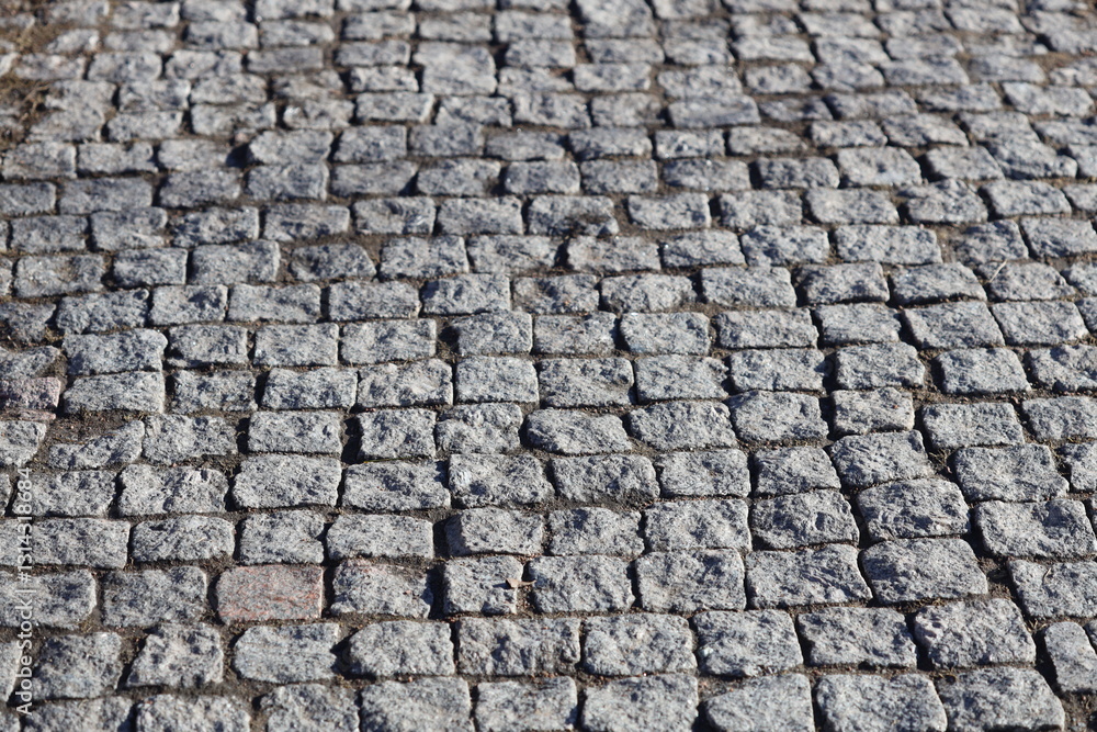 Poster a detailed view of a worn cobblestone street.