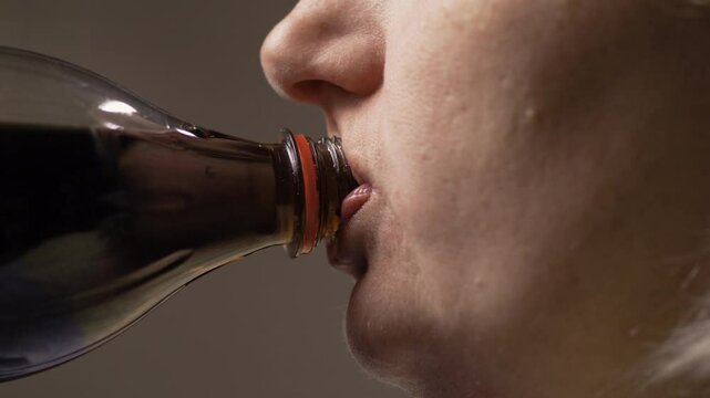 Close up of overweight woman drinking soda from bottle