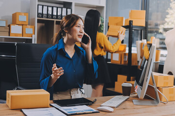 Asian SME business women use laptop computer checking customer order online shipping boxes at home....