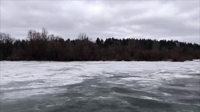 river in winter. Snow-covered blocks of ice on the river above the gray overcast sky. Frozen water surface on the lake, winter snowy day. River under a dark sky.