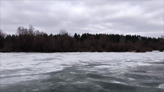 river in winter. Snow-covered blocks of ice on the river above the gray overcast sky. Frozen water surface on the lake, winter snowy day. River under a dark sky.