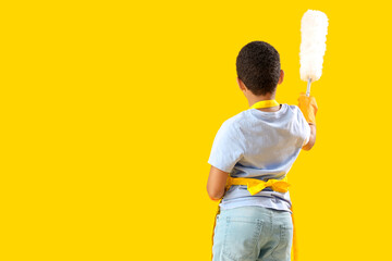 Little African-American boy with duster on yellow background, back view