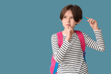 Thoughtful little boy with backpack and pencil on blue background