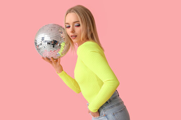 Beautiful young woman with disco ball on pink background
