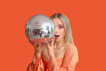 Beautiful shocked young woman with disco ball on red background